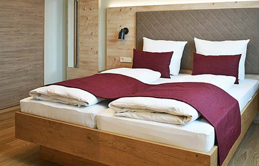 Ein Bett mit zwei Kissen und einem Kopfteil aus Holz.