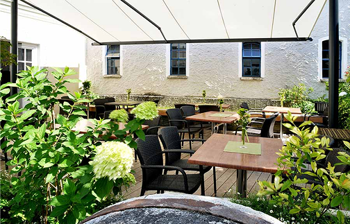 Restaurantterrasse mit Tischen und Stühlen, geschützt durch ein großes Awning.