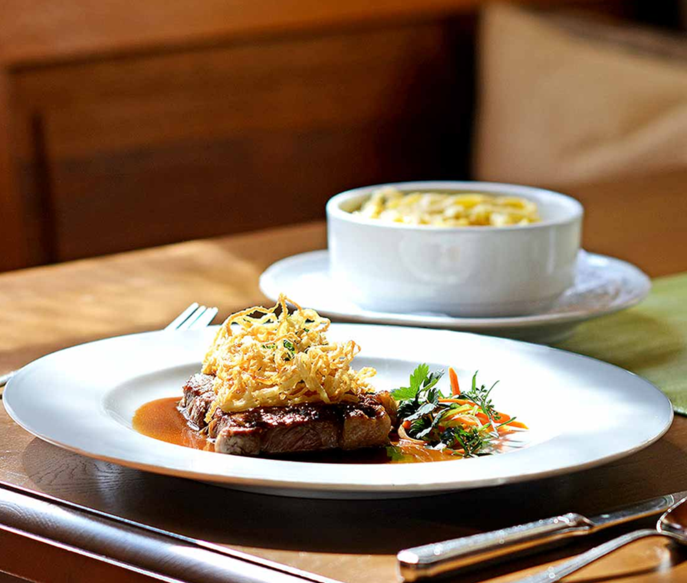 Ein Teller mit Essen und eine Schüssel Suppe stehen auf einem Tisch.